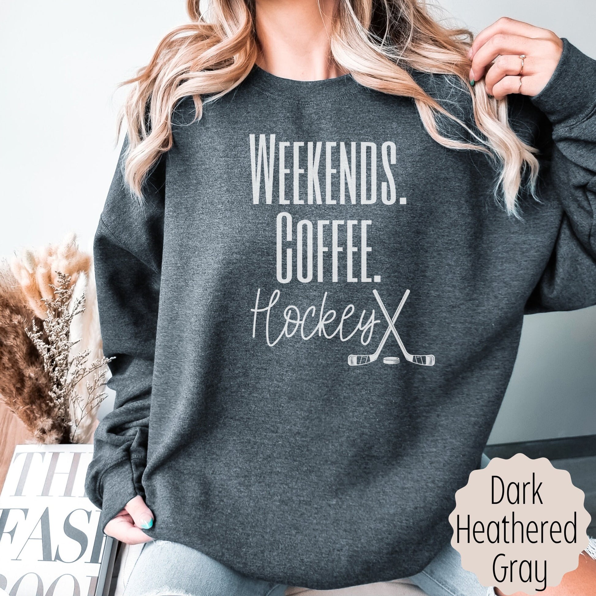 hockey lover sweatshirt that says weekends coffee hockey with a black outlined hockey sticks on the bottom. This sweatshirt comes in sand, white, black, gray, and heareth dark gray.