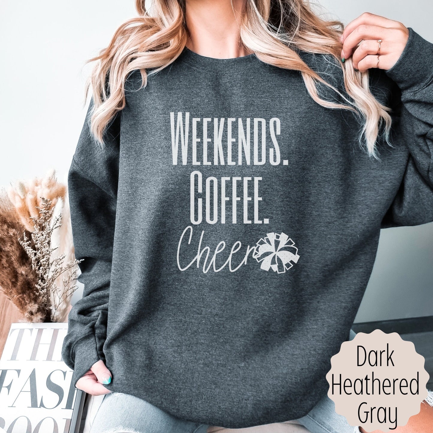 cheer mom sweatshirt that says weekends coffee cheer with a pom pom. This is plain text lettering and the sweatshirt comes in the colors ash grey, black, sand, white, and dark heathered grey.